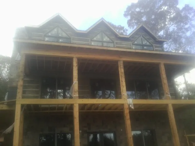 Dormers and porch framing on a large log home under construction — Roof Coating work by our crew in Maxwell